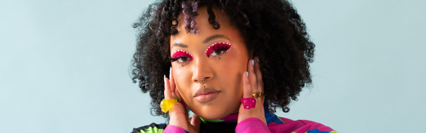 Close up of black woman with coloured eye makeup and rings