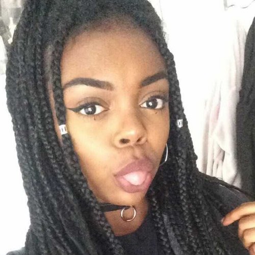 Young black woman with long braids sticks her tongue out at the camera.