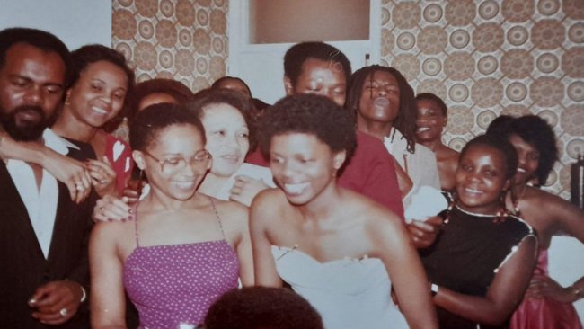 A group of young black people crammed into a living room.