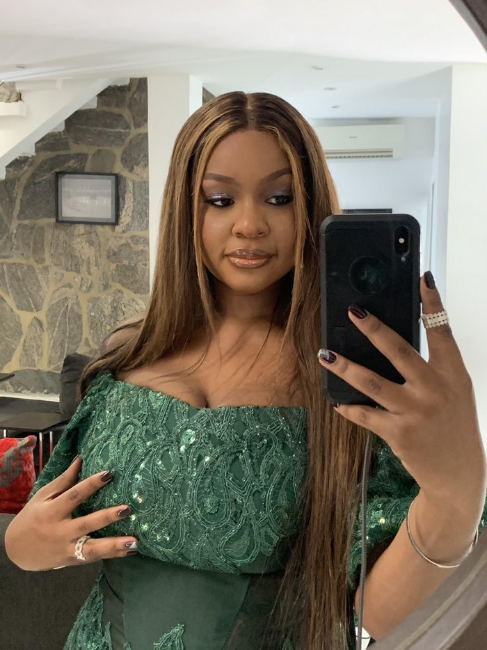 Faridah takes a mirror selfie wearing a green lace dress.