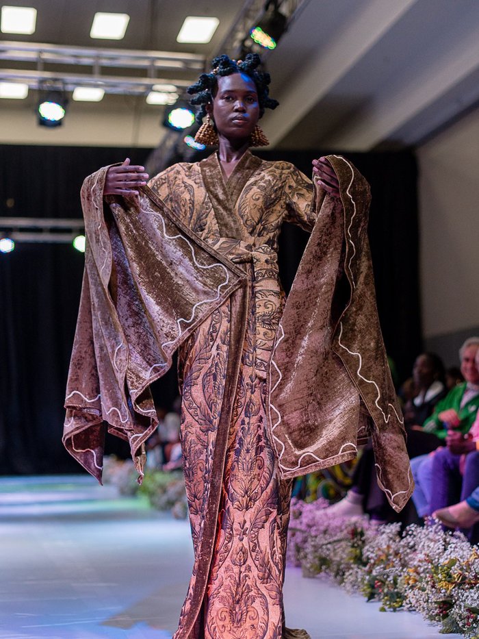 Black model wearing a long embroidered gown.
