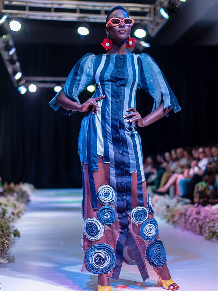 Black model wearing a dress made of repurposed denim and mesh.