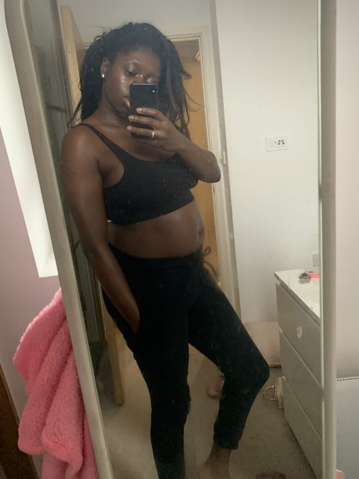Tobi takes a pregnant mirror selfie in a black crop top and black leggings