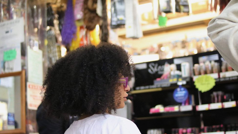 Inside a black hair shop. Person in the foreground, background out of focus.