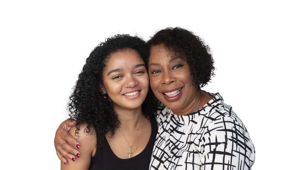 Young mixed race black woman is hugged by an older black woman.