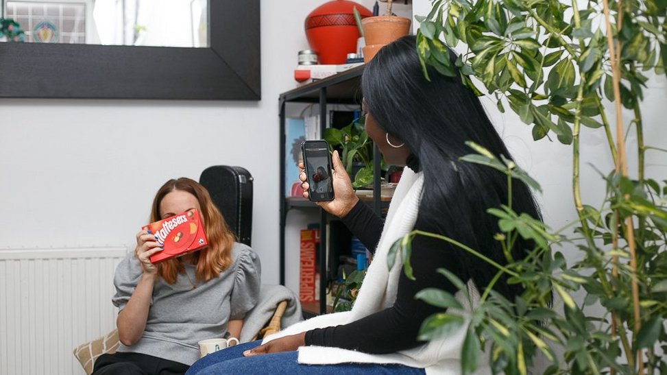 Woman takes a picture of her friend posing with Maltesers