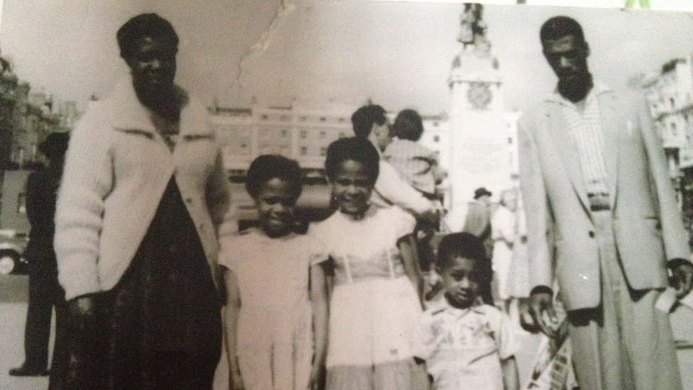 Black and white photograph of a black family of five, posing in front of a pier in the 1960s.