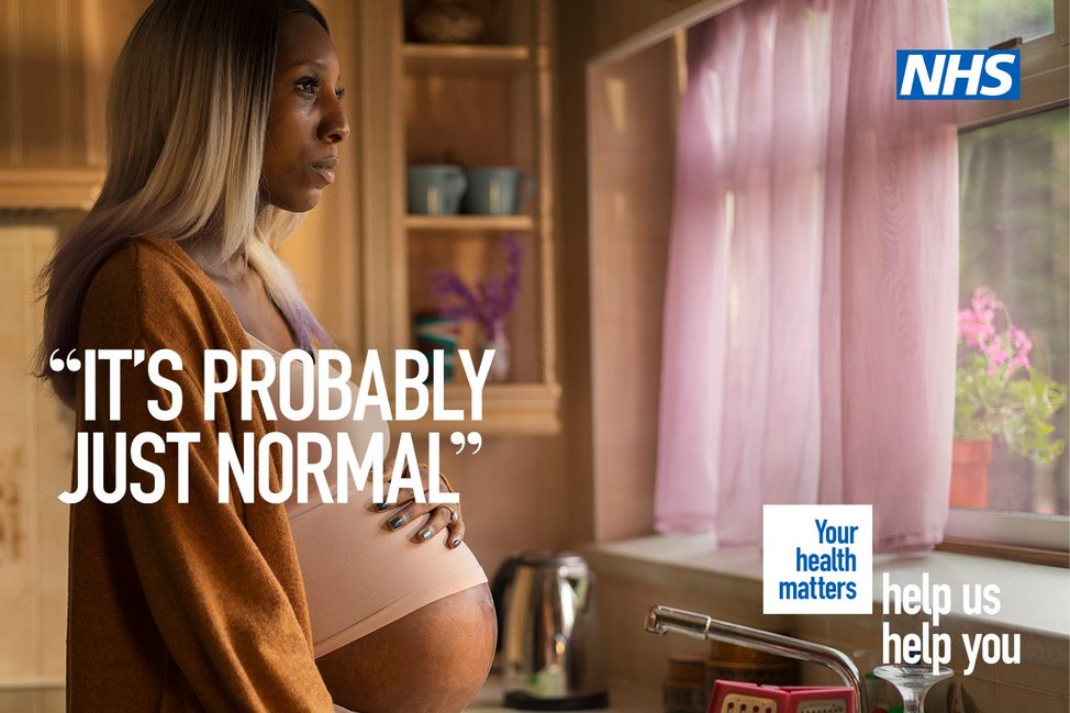 Image from NHS England's 'Help Us Help You' campaign. Heavily pregnant black woman stands in her kitchen looking out of the window resting a hand on her bump. Text reads, "It's probably just normal", then 'Your Health Matters'.