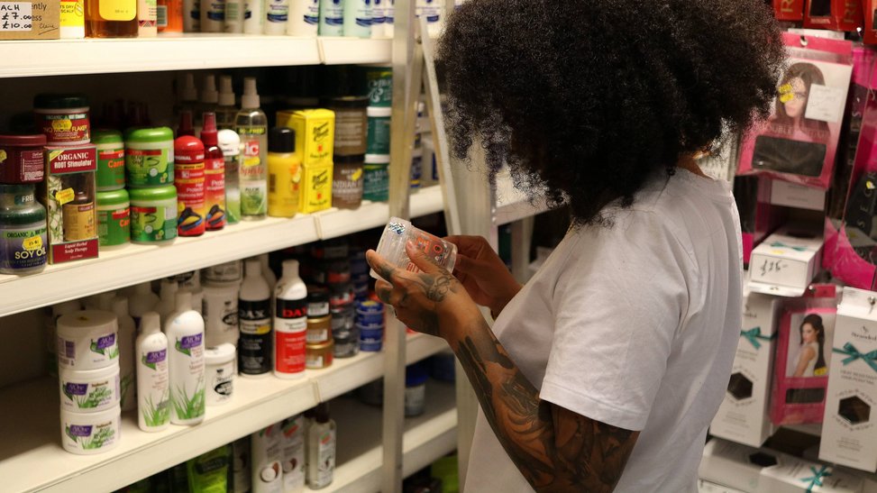 Person looks at a pot of hair gel.